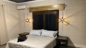A bedroom with a bed, a nightstand, a small table, a hanging light fixture, and a window with curtains. - Bourbon Trail & Relaxing rural spot. Restored Farmhouse on 22 private acres. (Lawrenceburg)