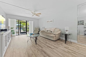 A modern living room with a sofa, coffee table, and a ceiling fan. - Siesta Escape - Ground Floor 2 BR 2 BA - on Inter-coastal and Free Trolley Stop (Siesta Key)