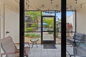 A room with a glass door leading to a balcony, a small table, and a chair. - Siesta Escape - Ground Floor 2 BR 2 BA - on Inter-coastal and Free Trolley Stop (Siesta Key)