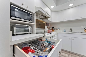 A modern kitchen with built-in appliances, a microwave, toaster, and a drawer organizer with utensils. - Siesta Escape - Ground Floor 2 BR 2 BA - on Inter-coastal and Free Trolley Stop (Siesta Key)