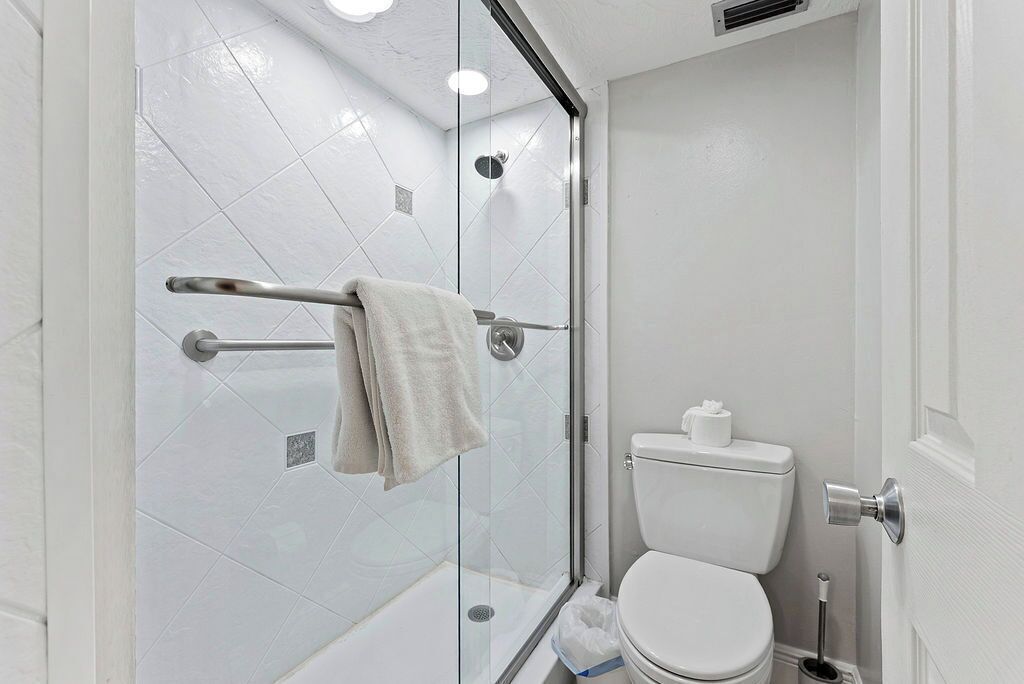 A modern bathroom with a glass shower enclosure, a white toilet, and a towel rack.