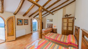 Une chambre avec deux lits, des poutres en bois, une vue sur l’extérieur et une armoire en bois.