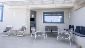 A modern outdoor seating area with white and grey chairs, a small table, and a bench. - Casa Blu, a house directly by the sea and in a central location in San Vito Lo Capo. (SAN VITO LO CAPO)
