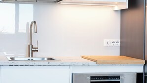 A modern kitchen with a stainless steel sink, a wooden cutting board, and a built-in dishwasher. - Casa Blu, a house directly by the sea and in a central location in San Vito Lo Capo. (SAN VITO LO CAPO)