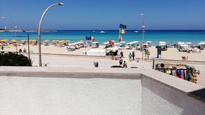 Una playa con sombrillas, banderas y un cielo azul despejado.