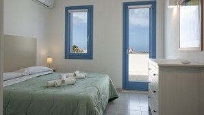 Habitación de hotel con una cama, un aparador y dos puertas que dan a un balcón.