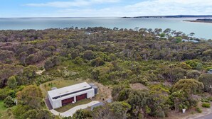 A modern house with a large garage, surrounded by dense bushland and a view of the sea. - Secluded Luxury (Greens Beach)