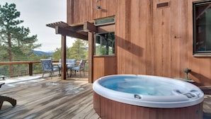 Eine Holzterrasse mit Whirlpool, Gartenmöbeln und einer Pergola.