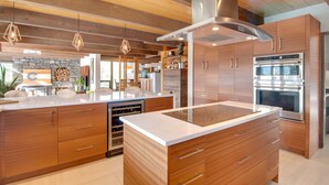 Une cuisine moderne avec des meubles en bois, un four encastré et un îlot central doté d’une plaque de cuisson.