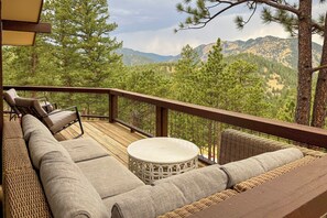Eine Terrasse mit einer Sitzecke und Stühlen, mit Blick auf eine Berglandschaft.