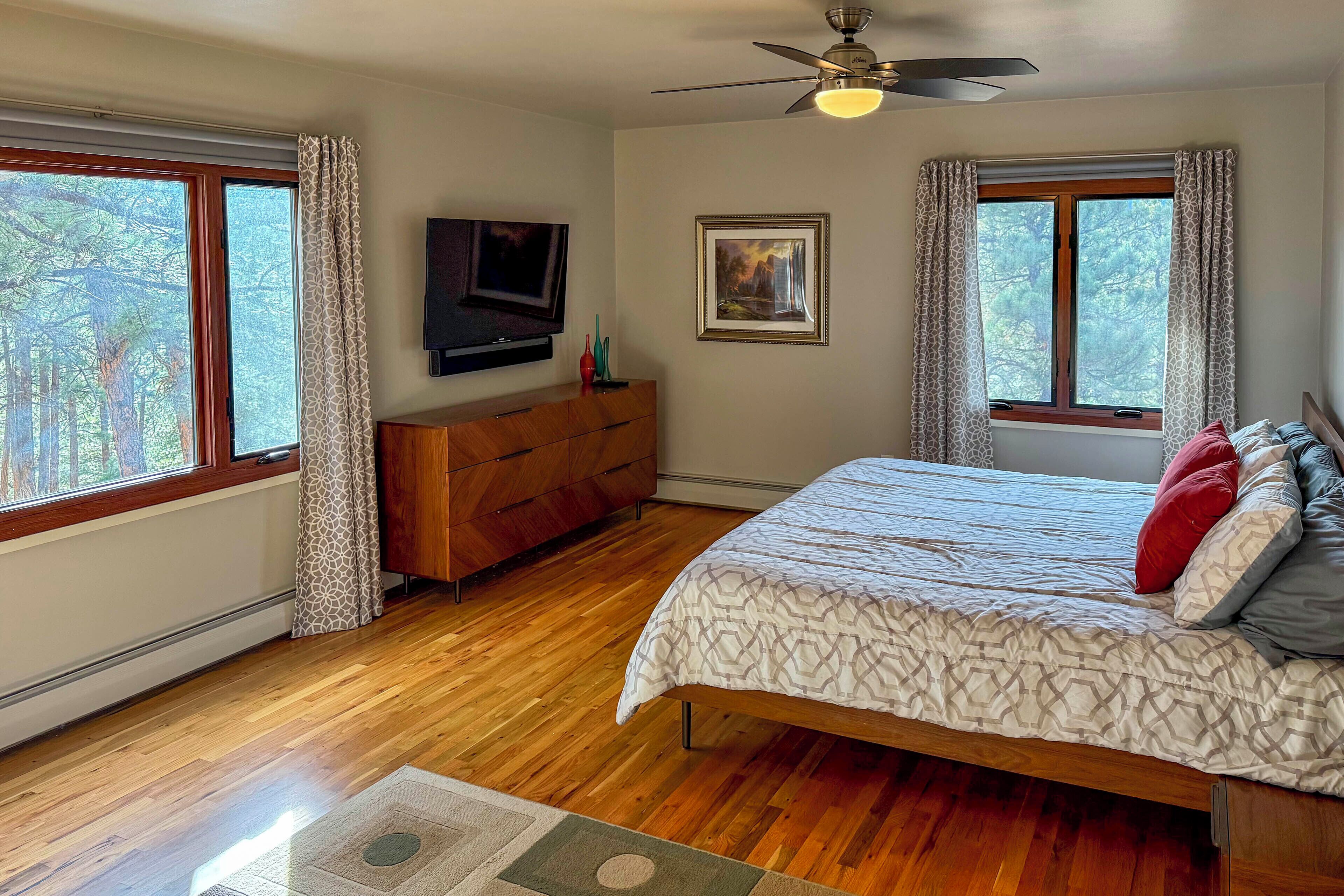 A bedroom with a bed, a dresser, a television, and a painting on the wall.