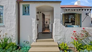 A white building with a red roof, a staircase leading to a door, and a garden with various plants. - Downtown SB Cottage! Charming Cozy and Recently Remodeled (Santa Barbara)