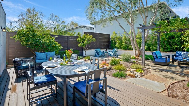 A patio with a round table and chairs, a pergola, and a seating area with blue cushions. - Downtown SB Cottage! Charming Cozy and Recently Remodeled (Santa Barbara)