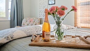 A bedroom with a bed, a bottle of champagne, a vase with flowers, and two glasses on a tray. - Downtown SB Cottage! Charming Cozy and Recently Remodeled (Santa Barbara)