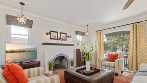 A living room with a fireplace, a large TV, and comfortable seating. - Downtown SB Cottage! Charming Cozy and Recently Remodeled (Santa Barbara)