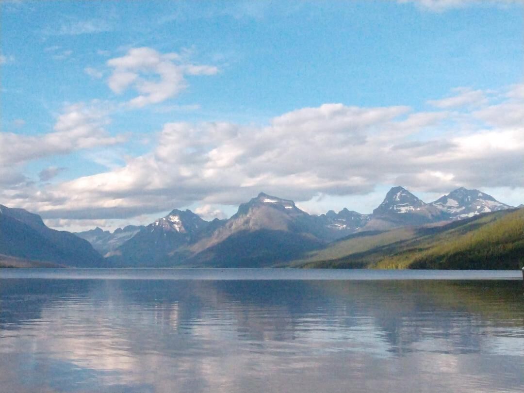 A calm lake with mountains in the background.