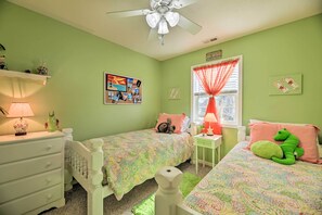 A room with two beds, a ceiling fan, a window with red curtains, and a wall with a colorful artwork. - Beaufort Pad w/ Patio: 3 Blocks to Waterfront! (Beaufort)