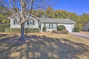 A single-story house with a garage, a well-maintained lawn, and mature trees. - Beaufort Pad w/ Patio: 3 Blocks to Waterfront! (Beaufort)