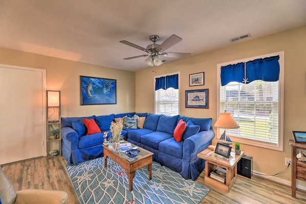 A living room with a blue sofa, a coffee table, and a ceiling fan. - Beaufort Pad w/ Patio: 3 Blocks to Waterfront! (Beaufort)