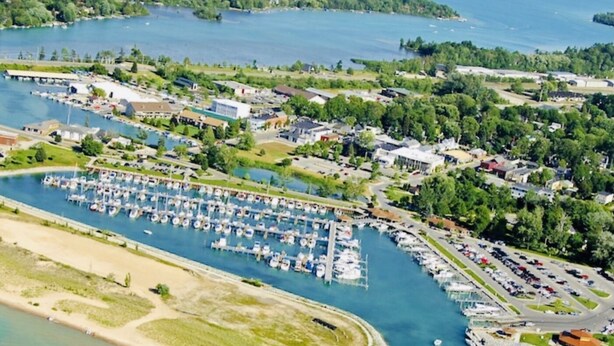 An aerial view of a marina with boats docked, surrounded by residential buildings and greenery.