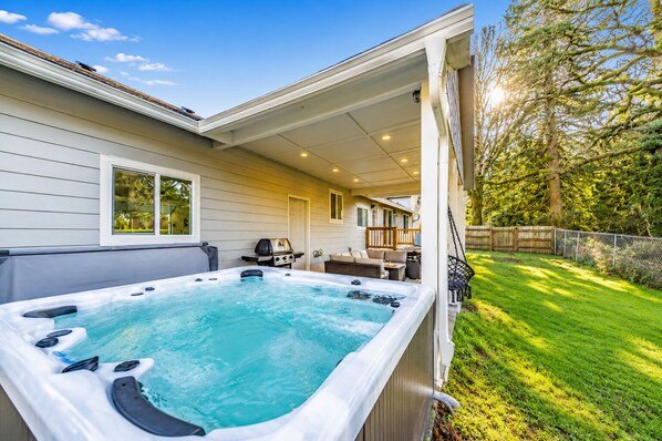 Un jardin avec un jacuzzi, du mobilier d’extérieur et un barbecue.