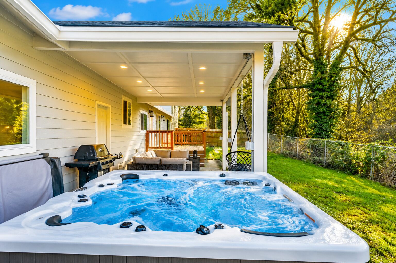 Un bain à remous dans un espace extérieur abrité, doté d’une terrasse en bois et d’un barbecue.