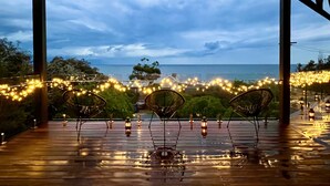 A covered outdoor seating area with chairs and string lights, overlooking a body of water. - Mount Martha Oceanfront Retreat | Pool, Spa, Views | Pet & Family Friendly (Mount Martha)