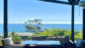 A room with a large window overlooking a scenic view of the ocean and greenery. - Mount Martha Oceanfront Retreat | Pool, Spa, Views | Pet & Family Friendly (Mount Martha)