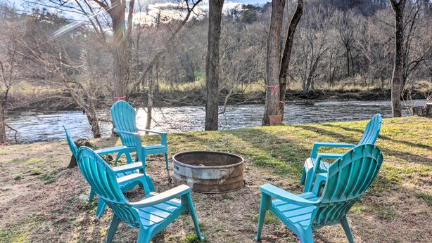 Een terras aan het meer met turquoise Adirondack-stoelen en een vuurplaats.