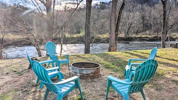 Een terras aan het meer met turquoise Adirondack-stoelen en een vuurplaats.