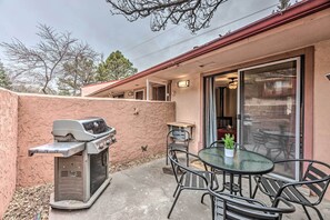 Une terrasse équipée d’un barbecue, de meubles d’extérieur et d’une porte-fenêtre coulissante donnant sur un espace intérieur.