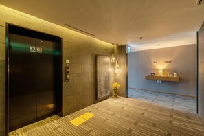 A hotel lobby with an elevator, a reception desk, and a wall-mounted light fixture. - Paju Mate Hotel (Paju)