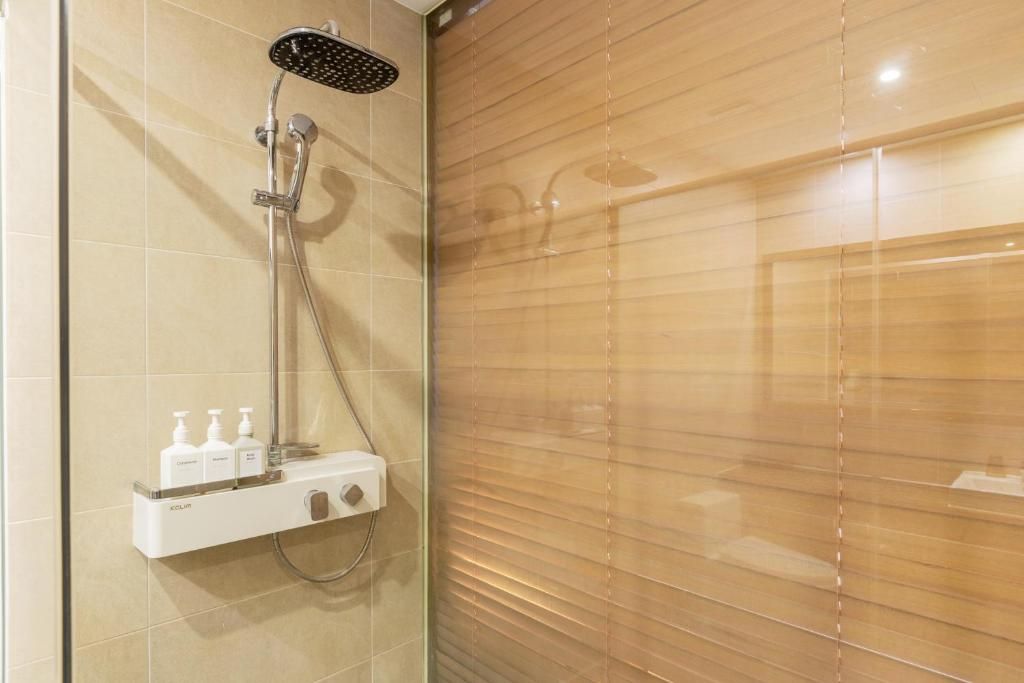A shower with a handheld showerhead and a wall-mounted control panel.