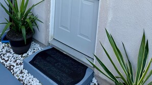 A white door with a keypad lock, a potted plant, and a doormat. - Private Studio 4 minutes from Strip !!! (Las Vegas)