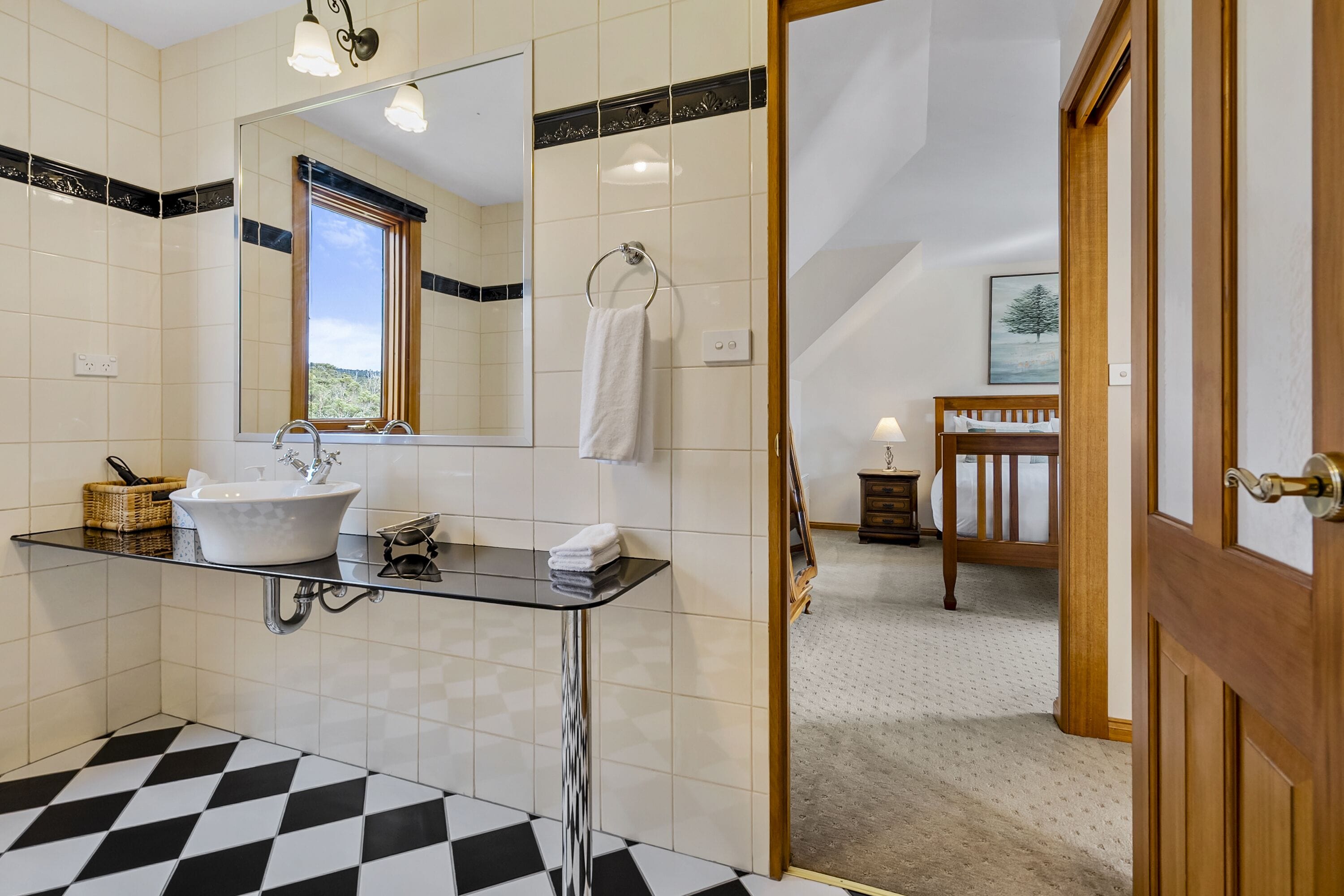 A modern bathroom with a glass sink, white tiles, and a checkered floor.