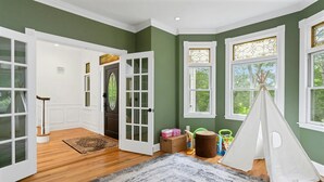 A room with green walls, wooden flooring, a white door, and a window with a view of trees. - Private Luxury Stay in Expansive Home & Property (EASTON)