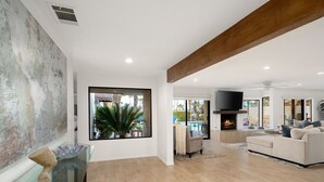 A spacious living room with a fireplace, a large window with a view of a pool, and a modern interior design. - Everything you want! Pool/spa, Golf Course, Mountain Views (Palm Desert)