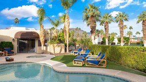 A pool area with lounge chairs, palm trees, and a building with a brown awning. - Everything you want! Pool/spa, Golf Course, Mountain Views (Palm Desert)