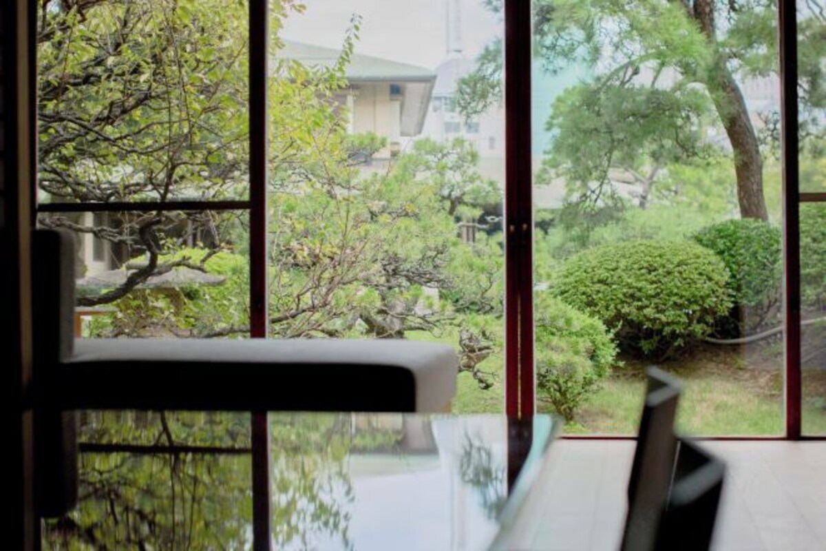 A room with a view through a window, a table, and a chair.