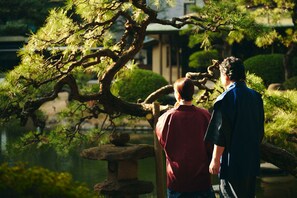 A traditional Japanese garden with a stone lantern, pine trees, and a pond. - Suisui Garden Ryokan (Kitakyushu)