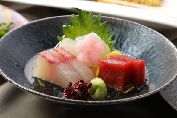 A dish with various seafood and garnishes on a dark plate. - Suisui Garden Ryokan (Kitakyushu)