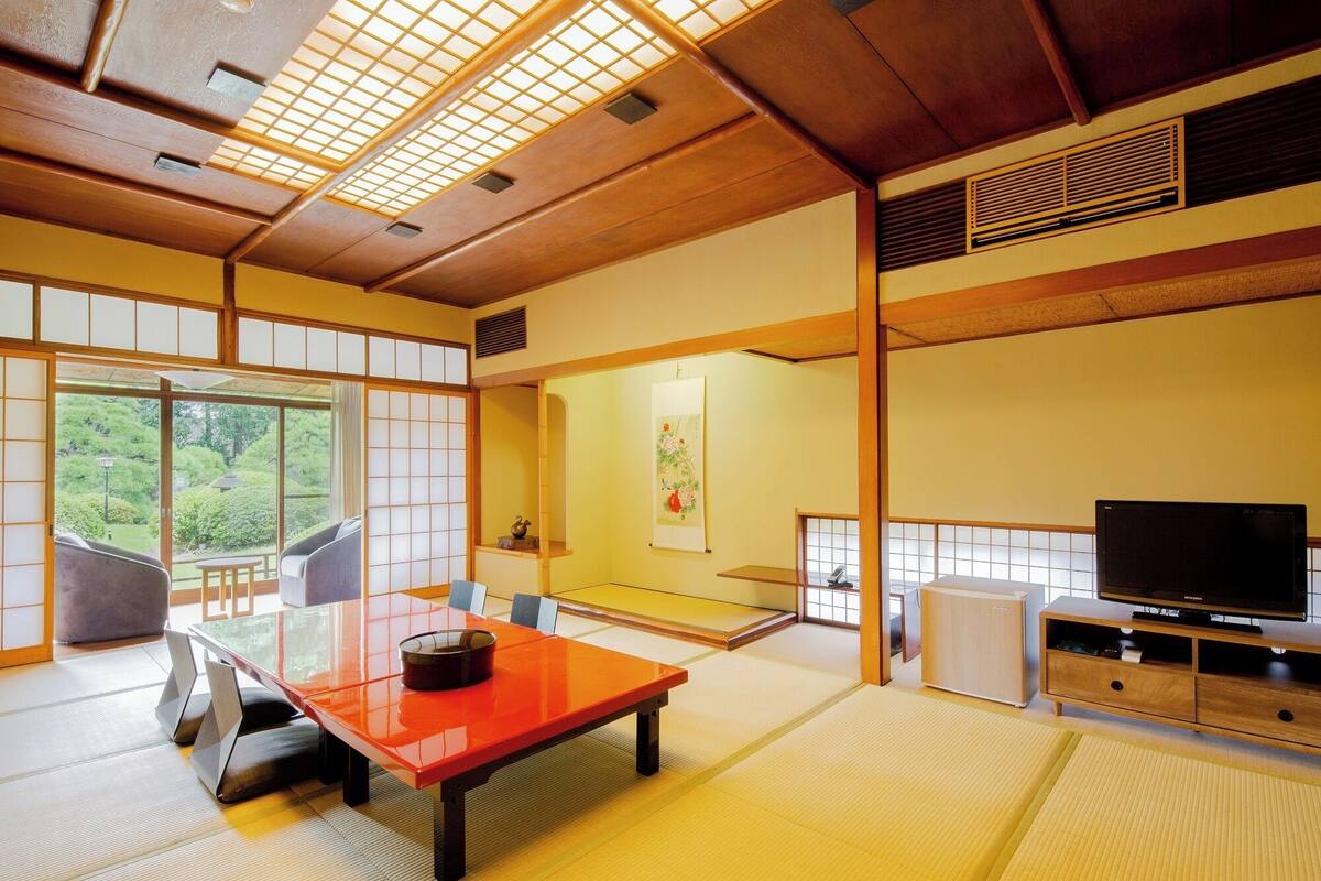 A traditional Japanese-style room with tatami flooring, a low table, and a television.