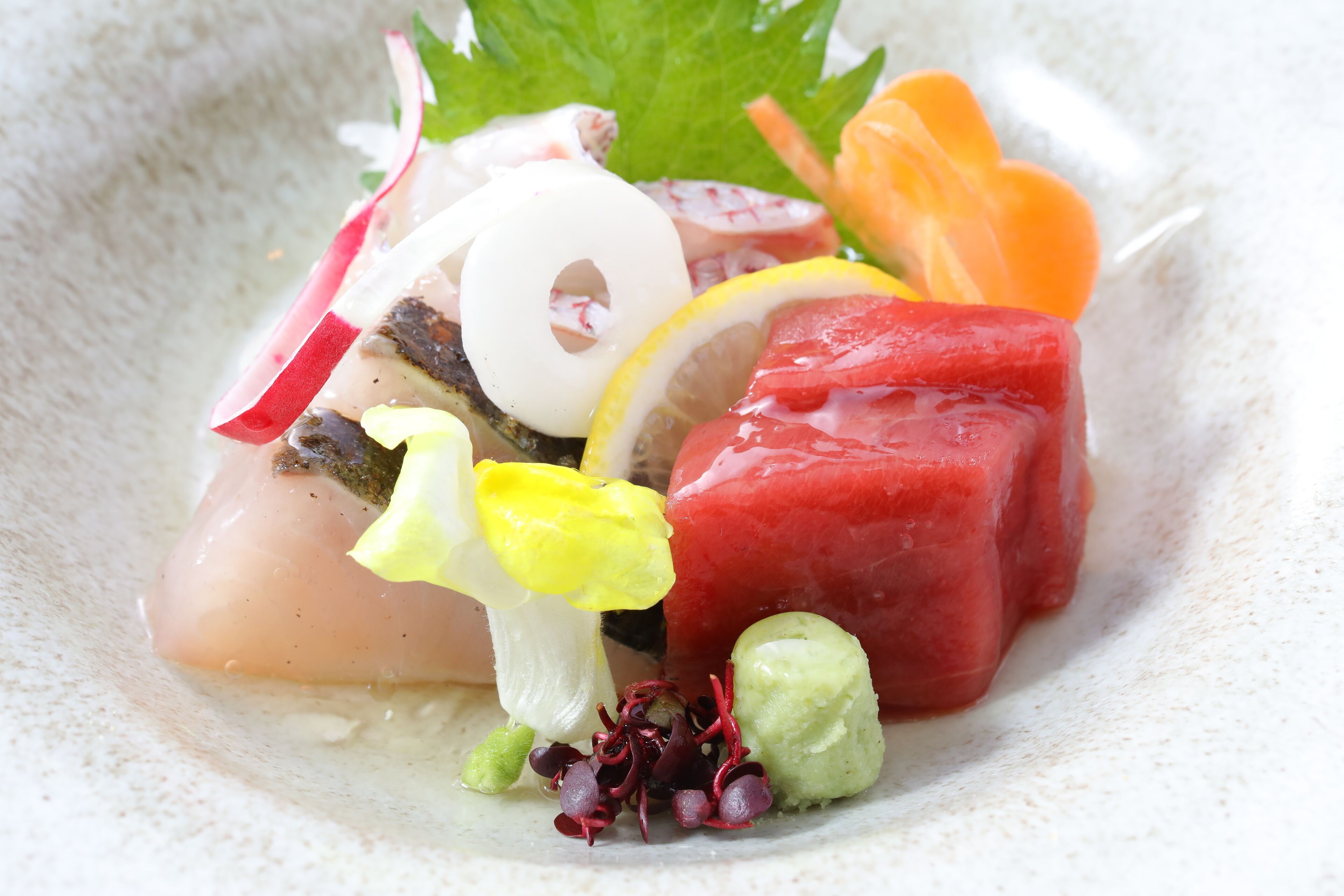 A dish with various ingredients including radish, lemon, and possibly some type of meat or fish.