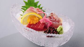 A clear glass bowl with various types of sashimi arranged on a bed of ice.