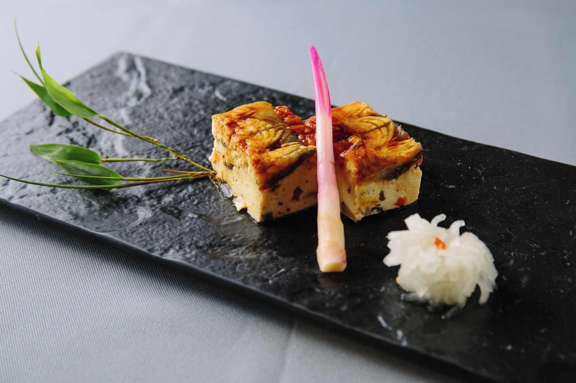 Una porción de pastel con un palito rosa sobre un plato negro.