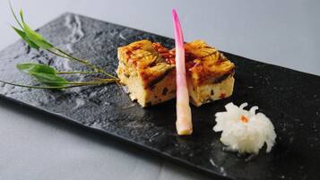 Una porción de pastel con un palito rosa sobre un plato negro.