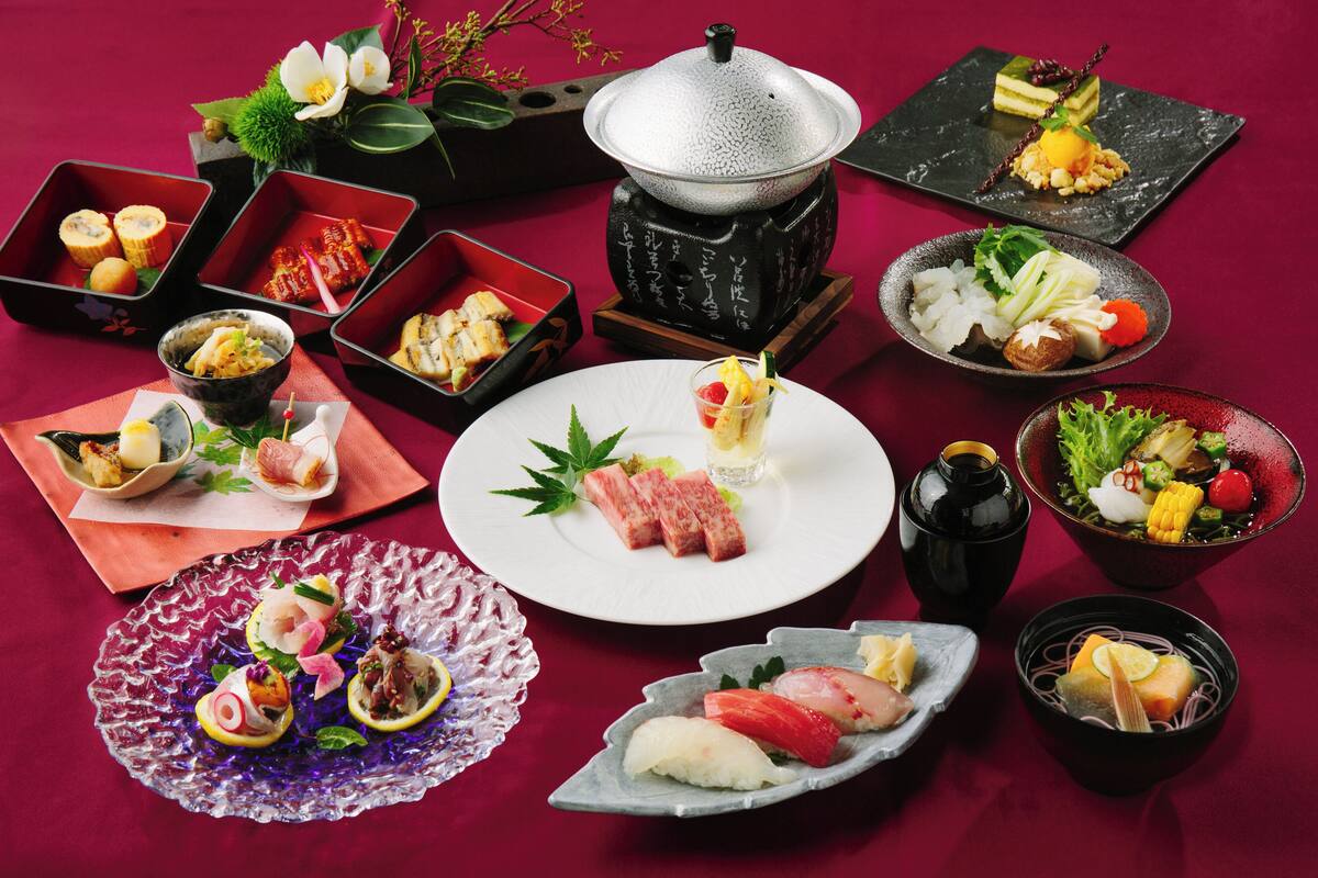 A variety of Japanese dishes arranged on a table with a red tablecloth.