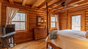 Une chambre située dans un chalet en rondins, comprenant un lit, une commode, une coiffeuse, un miroir et un téléviseur.