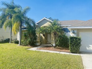 Set amidst a lush lawn and palm trees, this single-story house offers a serene retreat.