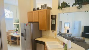 Una cocina moderna con armarios de madera, un refrigerador de acero inoxidable y una encimera blanca.